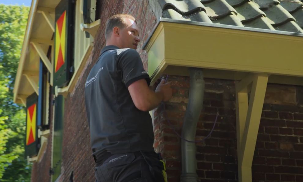 Monteur van CameraInstallatie werkt aan een camera onder de dakrand