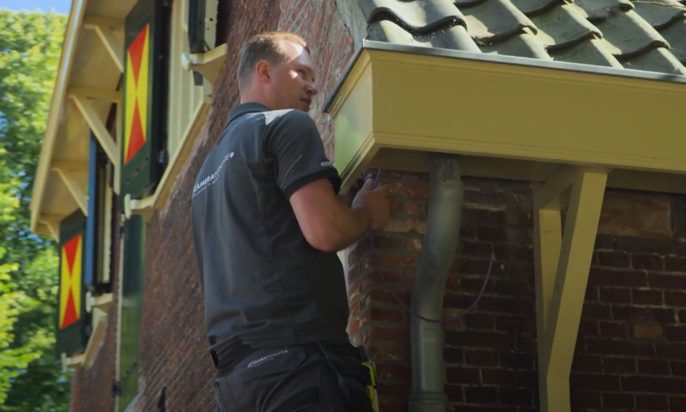 Monteur van CameraInstallatie werkt aan een camera onder de dakrand