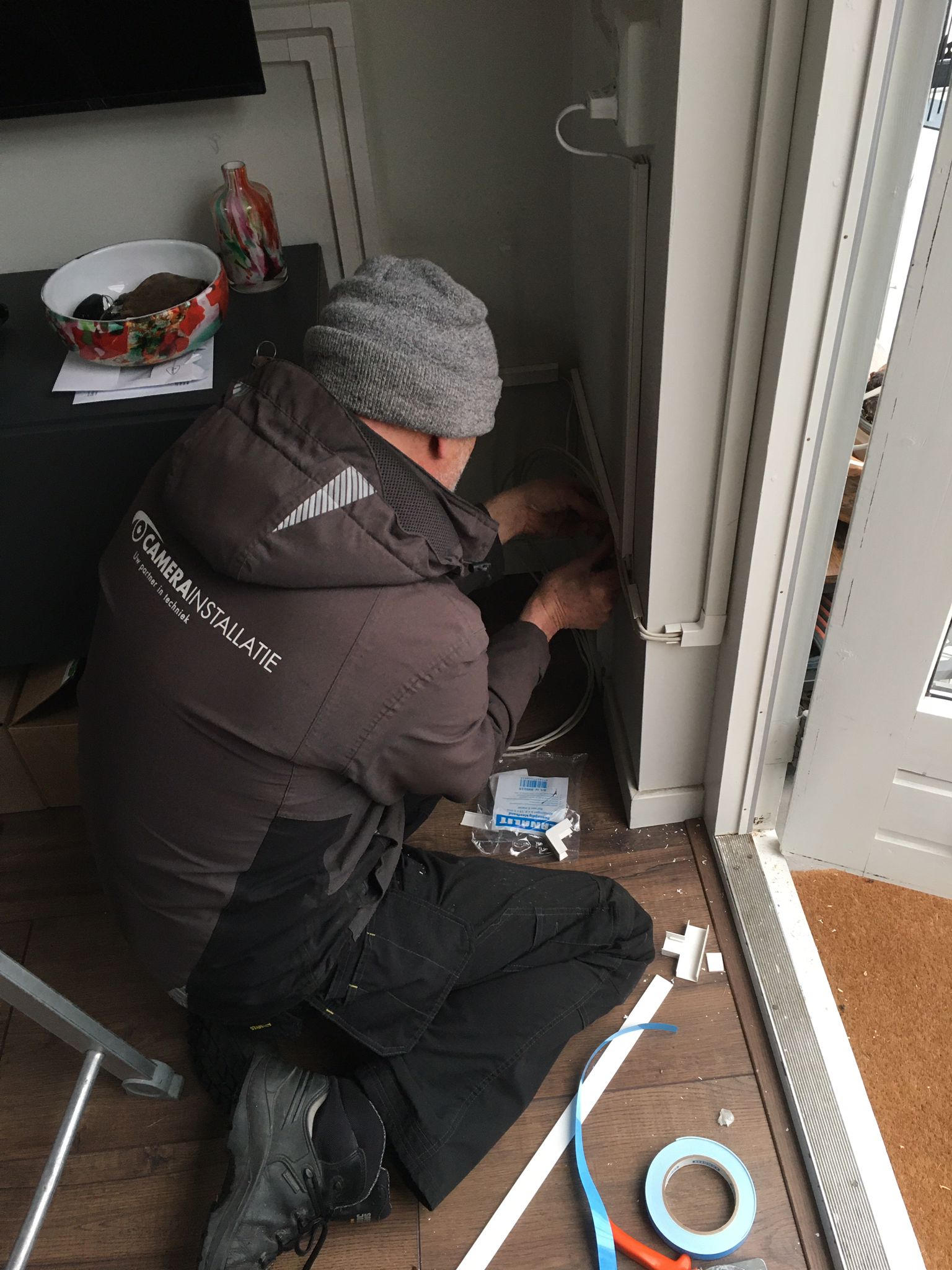 Monteur legt de bekabeling netjes langs een deurkozijn binnen