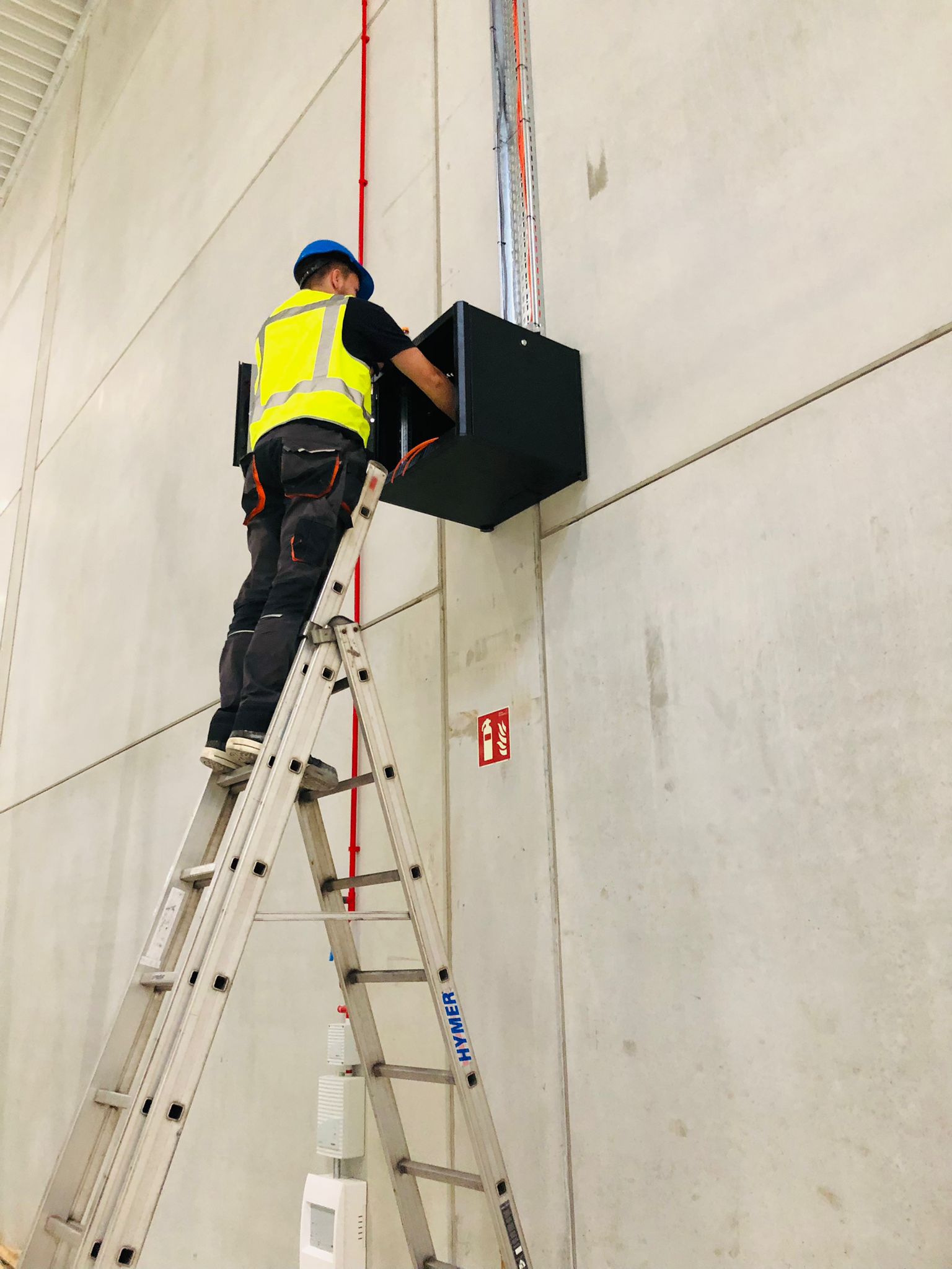 Monteur van CameraInstallatie op een ladder monteert een technische kast