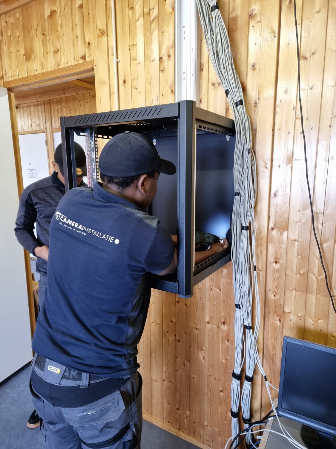 Monteur van CameraInstallatie plaatst de wandkast waar de recorder in komt