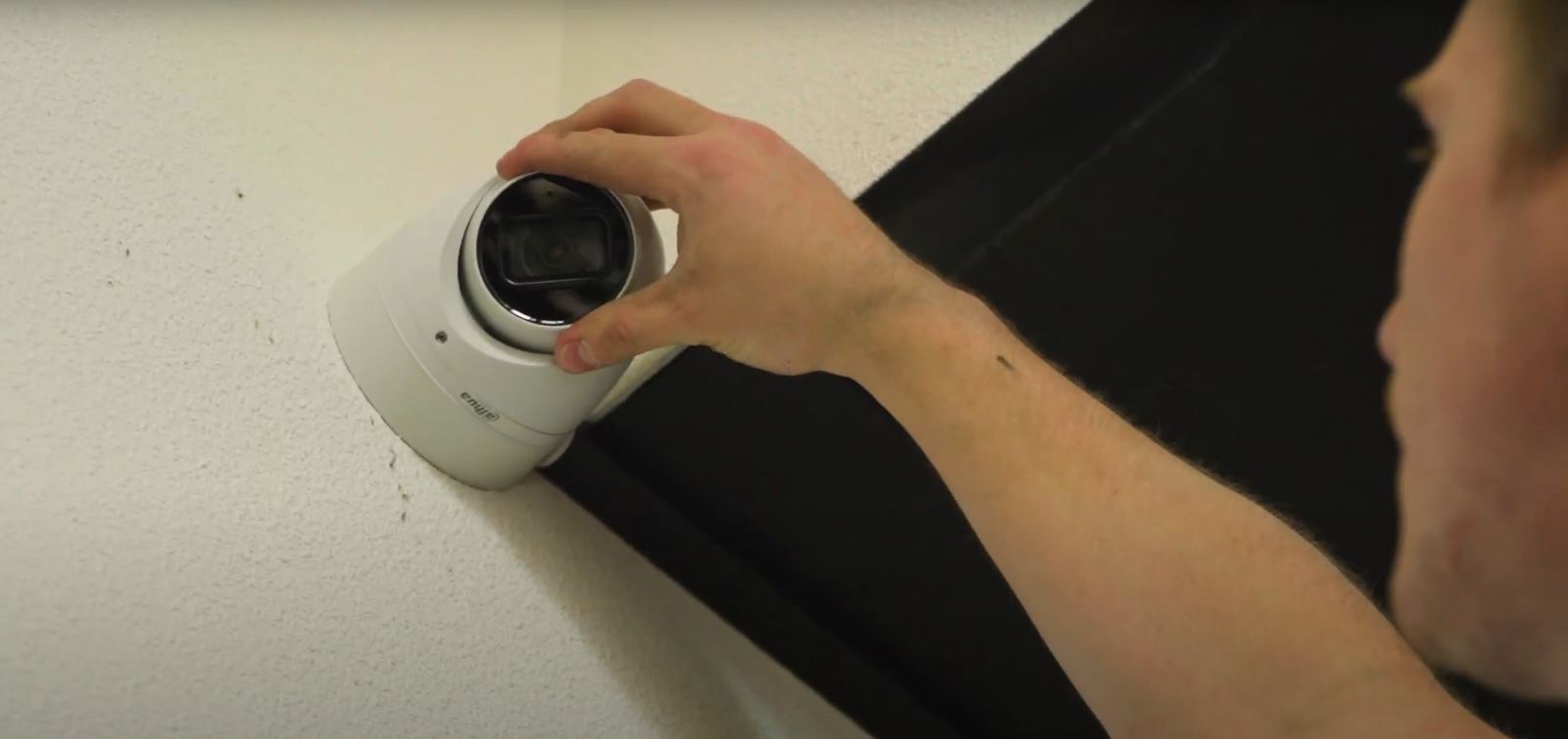 Monteur plaatst een witte beveiligingscamera tegen het plafond