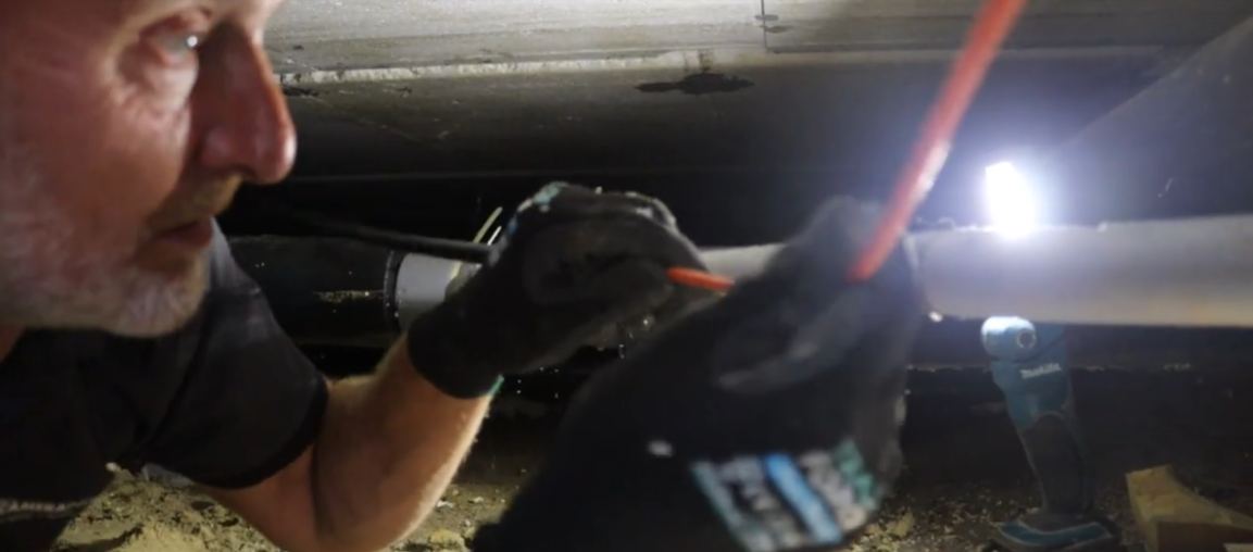 Monteur van CameraInstallatie trekt kabel door de kruipruimte
