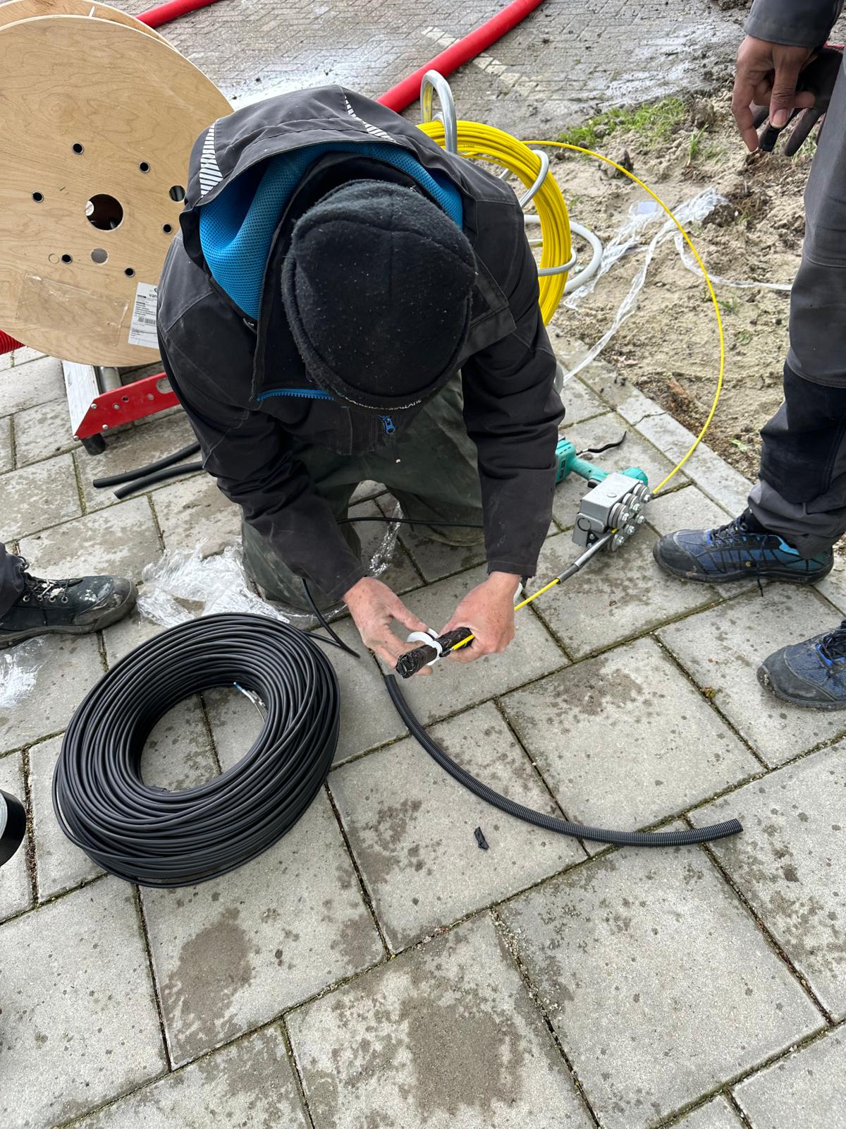 Monteur maakt buiten een glasvezelverbinding met kabelhaspel en trekband