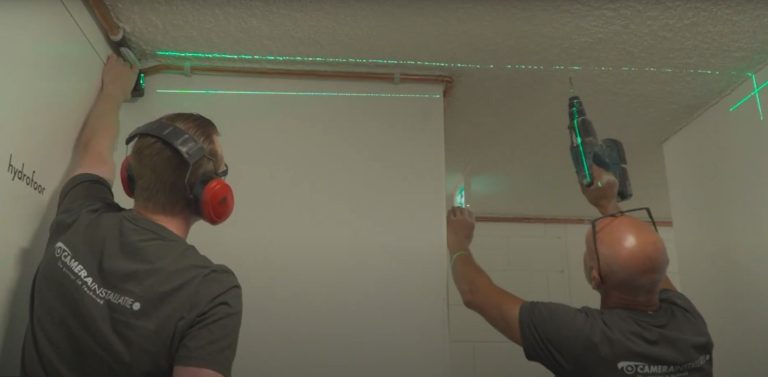 Twee monteurs van CameraInstallatie.nl lijnen met een laser de positie van een camera uit