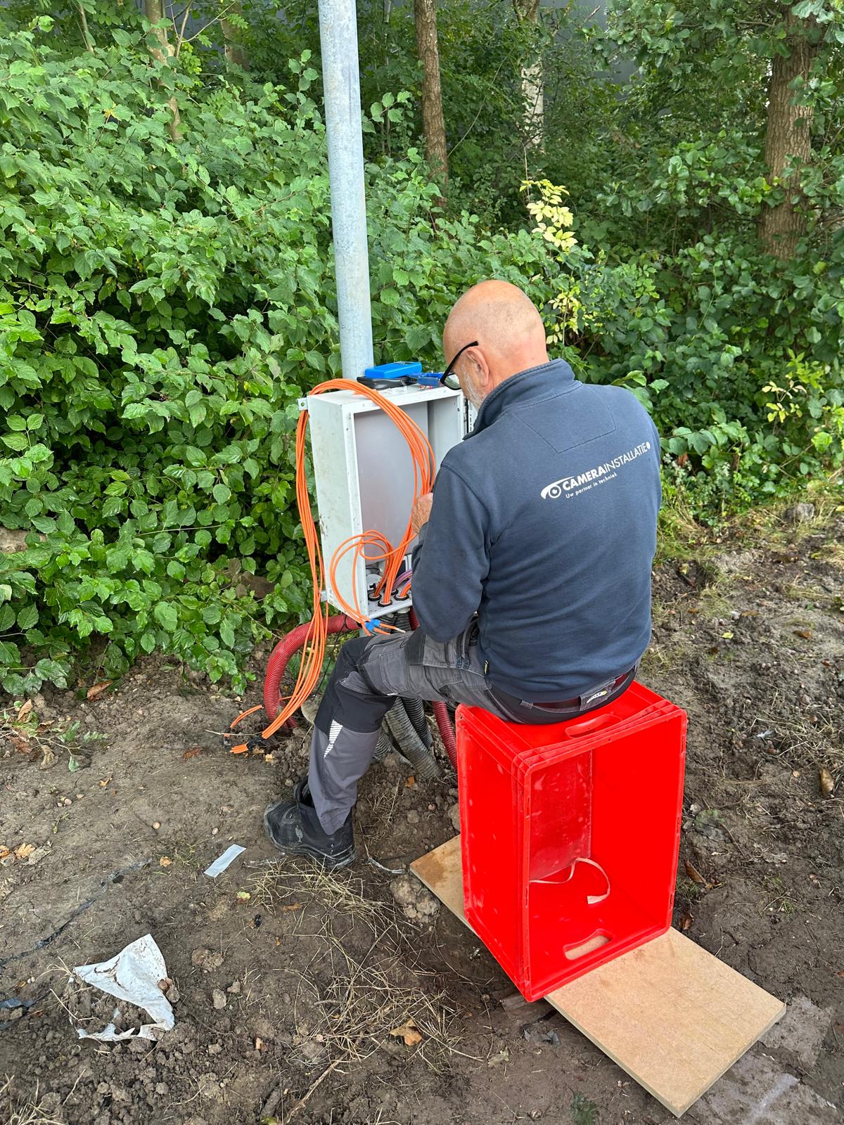 Monteur van CameraInstallatie werkt aan de aansluitkast bij een buitenpaal