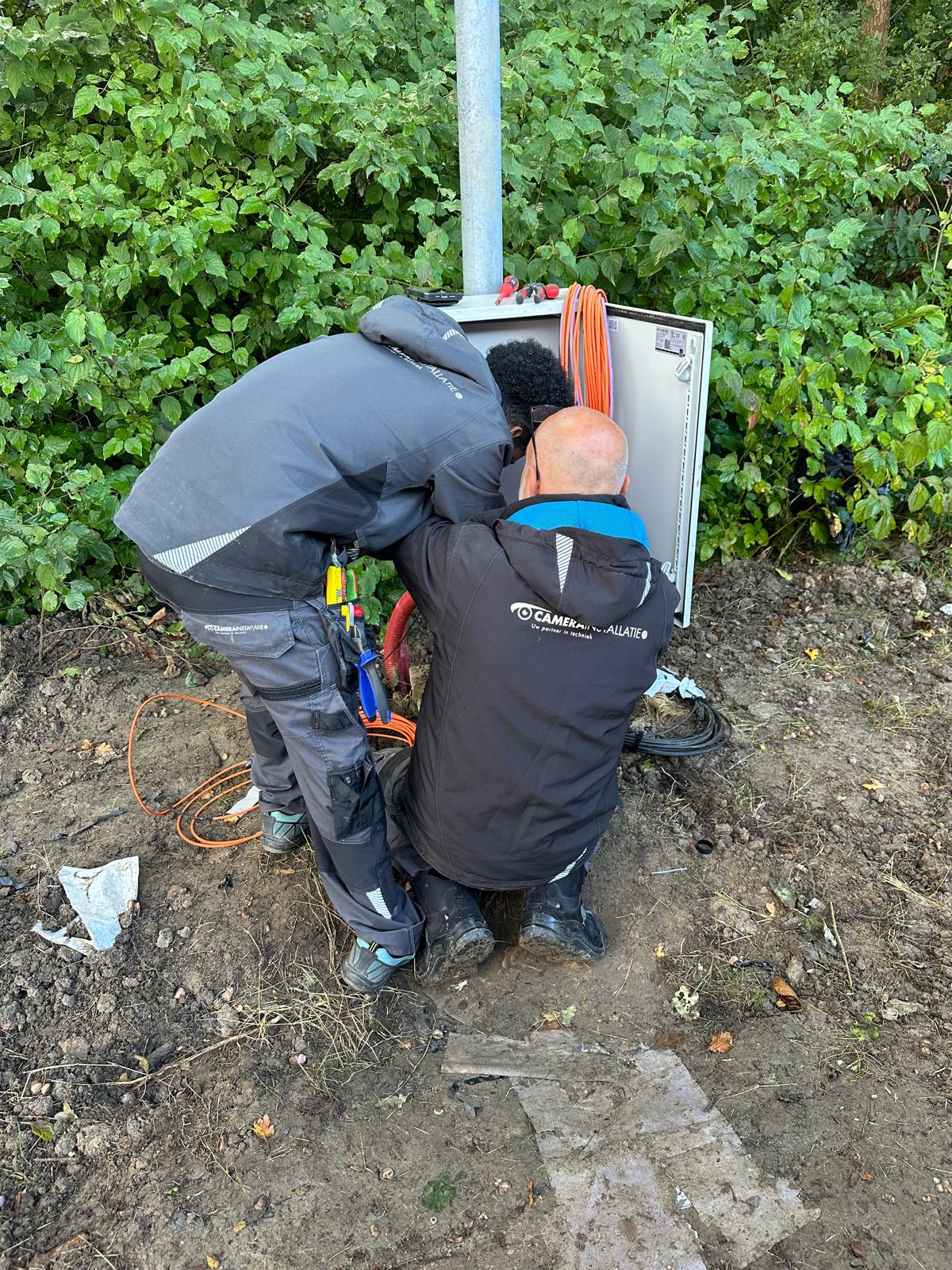 Monteurs werken samen aan de aansluitkast onderaan een buitenpaal