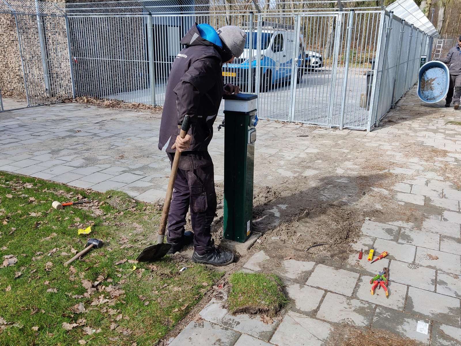 Monteur van CameraInstallatie graaft de kabel in bij een paal op het terrein