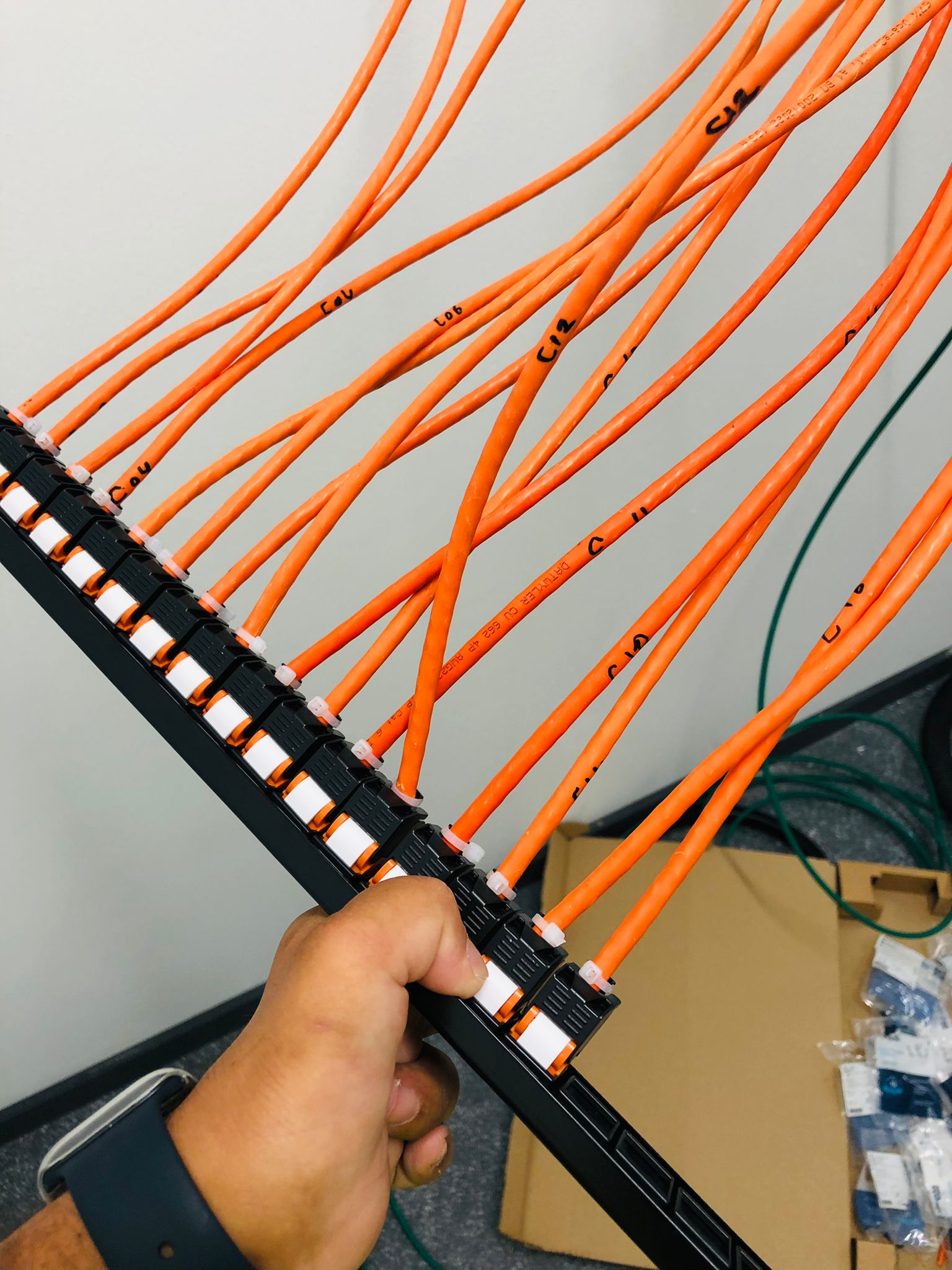Genummerde oranje datakabels netjes afgemonteerd op het patchpaneel