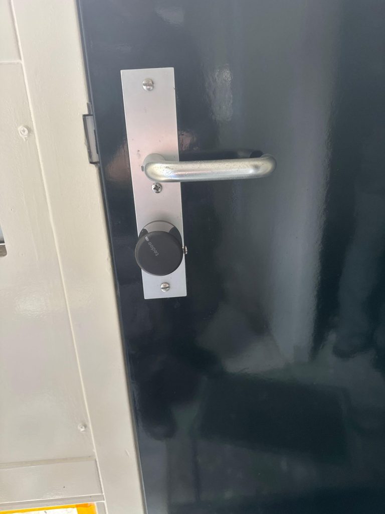 Zwart Tedee slim slot op de binnenzijde van een deur, over de bestaande cilinder