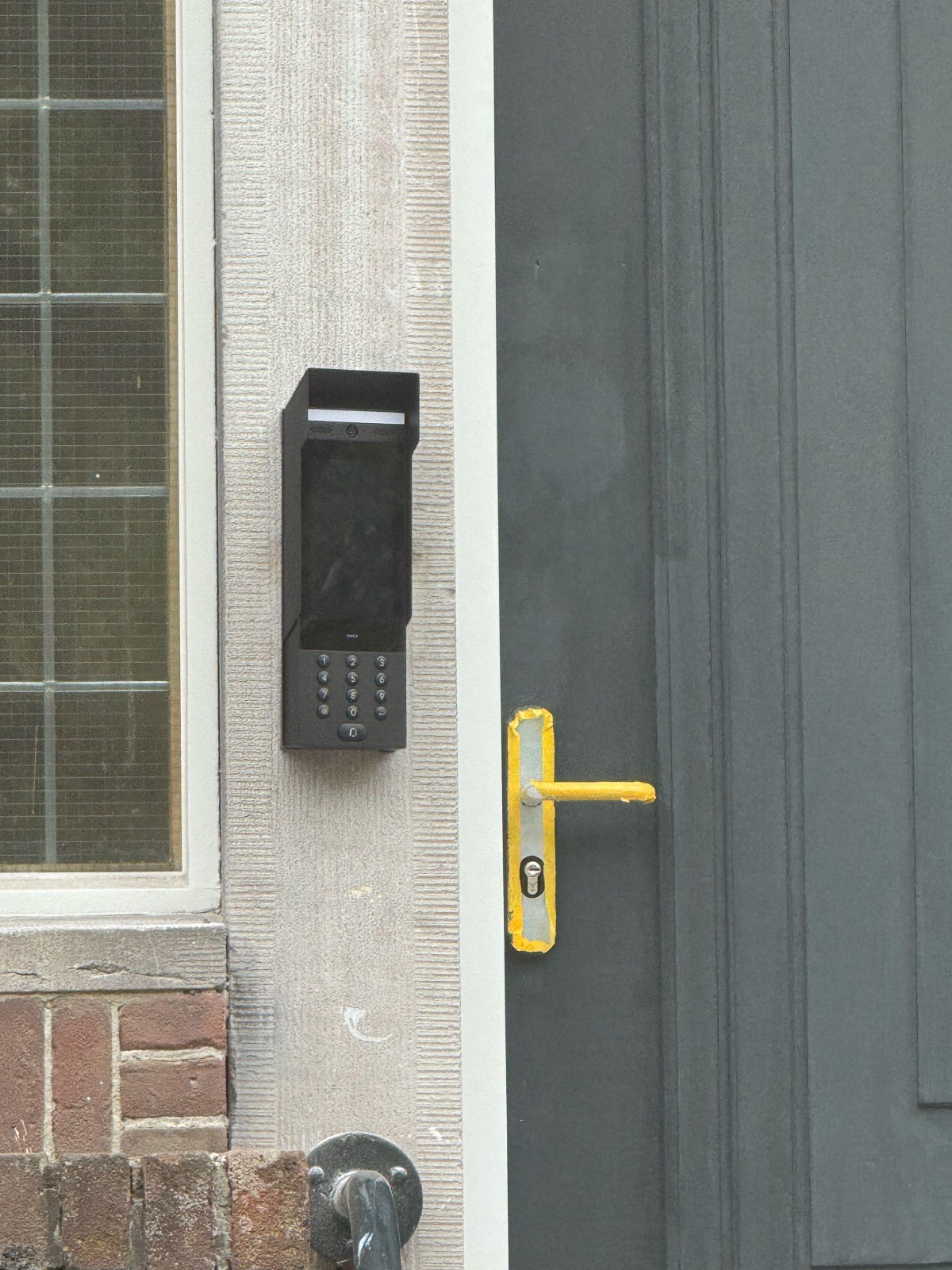 Zwart codepaneel met keypad naast een voordeur, netjes op de gevel gemonteerd
