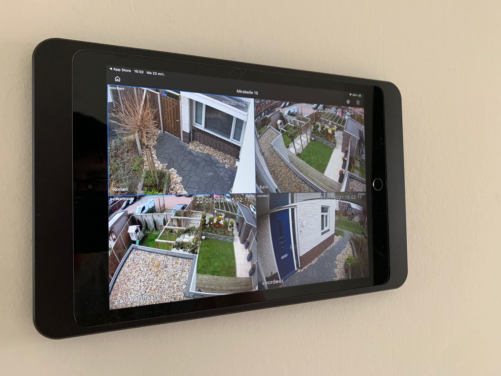 Touchscreen aan de wand met vier live camerabeelden van een woning