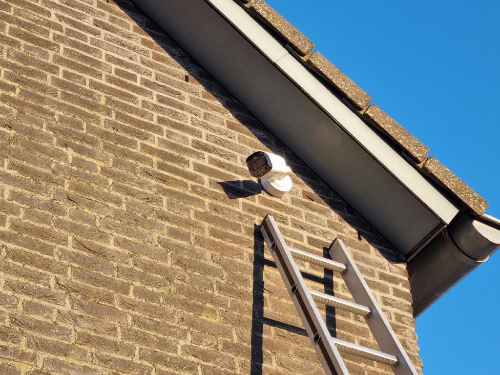 Camera onder de dakgoot van een woning, gezien vanaf de ladder