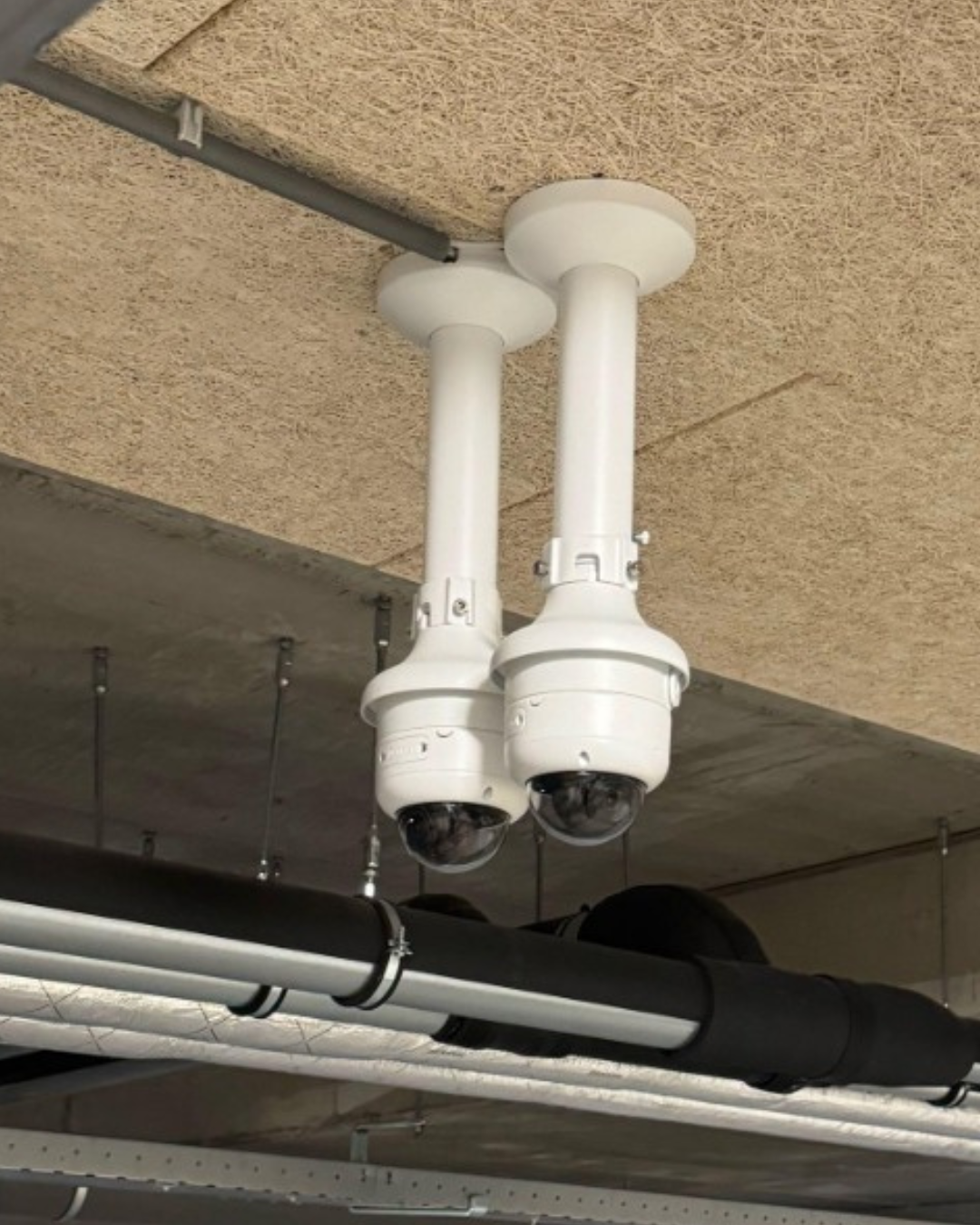 Twee domecamera's aan een plafond, elk gericht op een andere kant van de ruimte