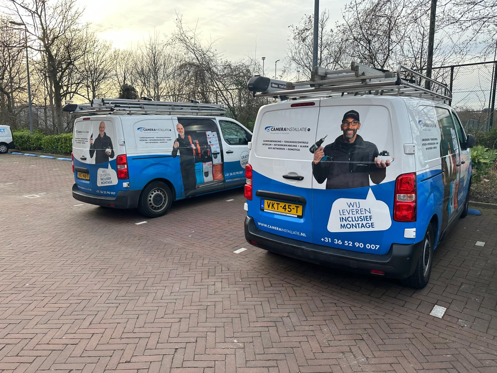 Twee servicebussen van CameraInstallatie naast elkaar op een parkeerterrein