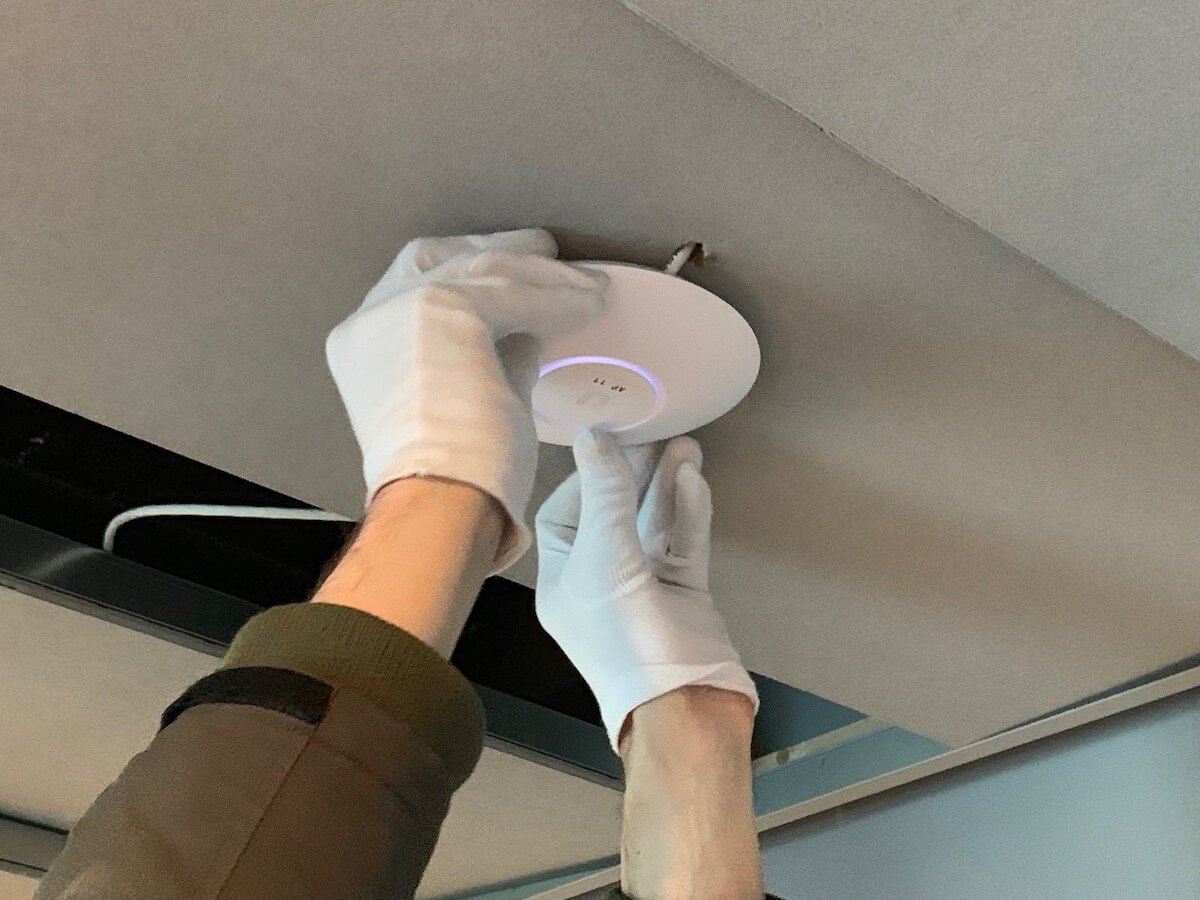 Onze monteur monteert een UniFi access-point aan het plafond