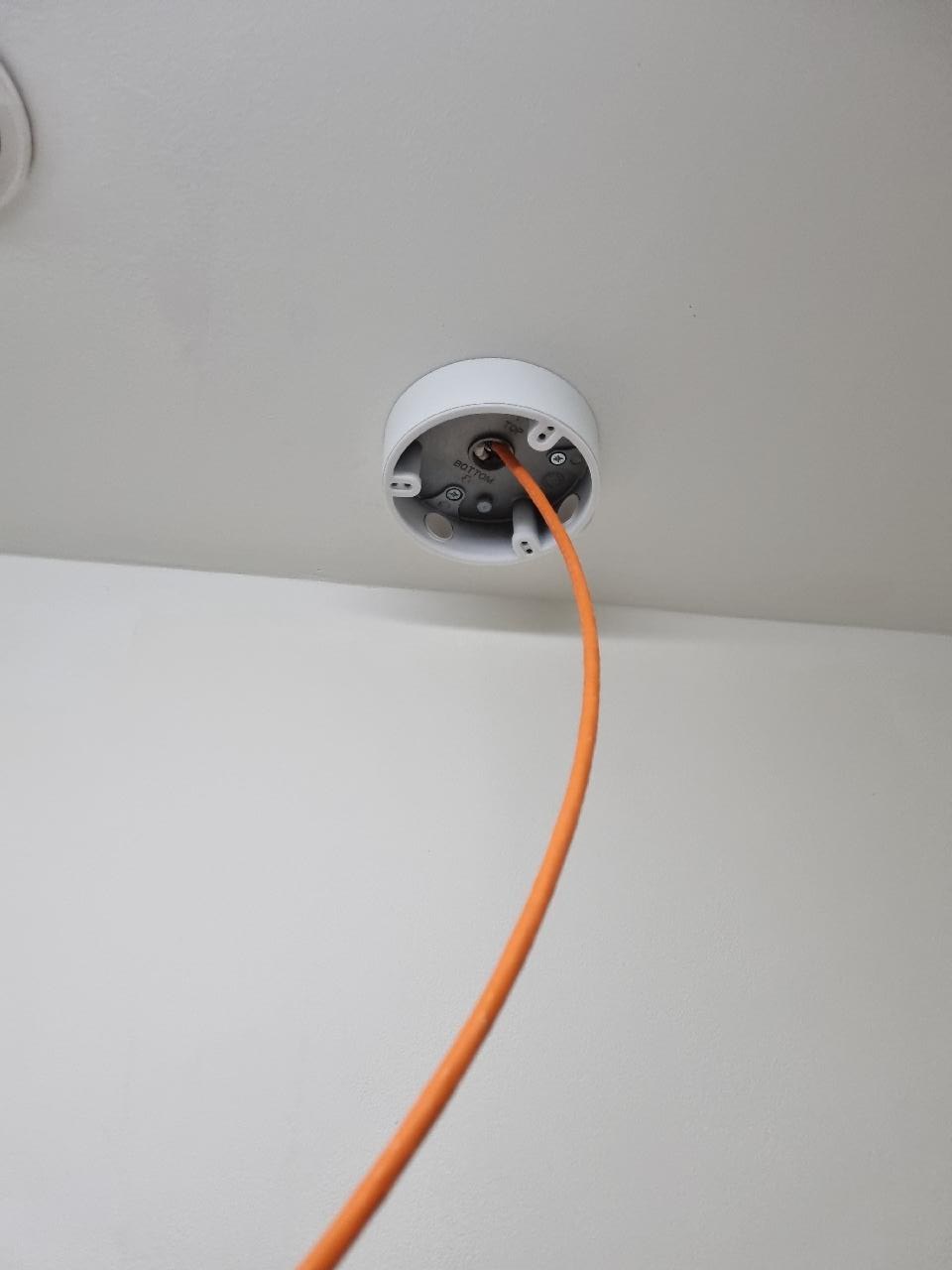Oranje kabel komt netjes uit het plafond op de camerapositie