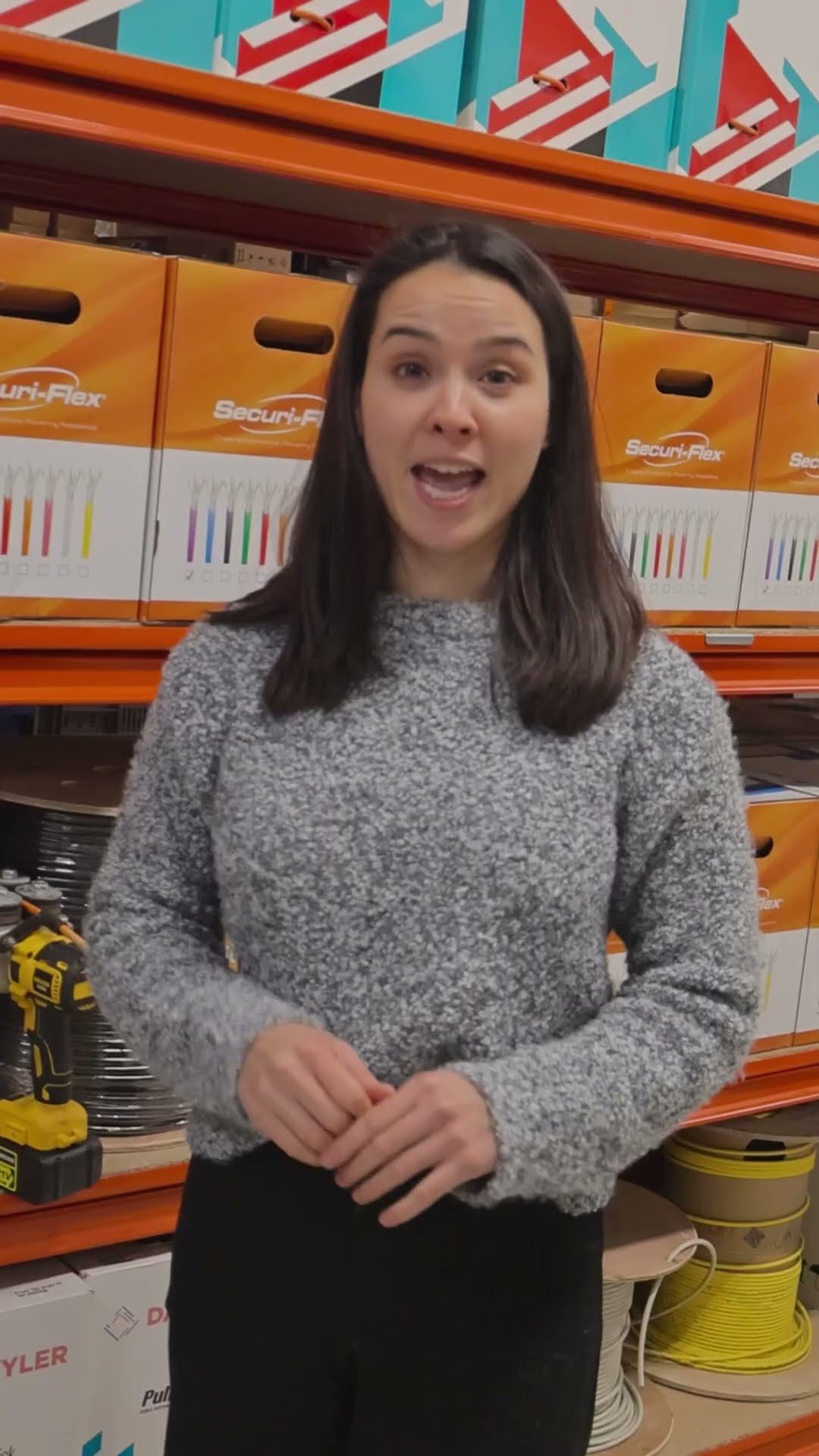 Videotegel: onze medewerker staat in ons magazijn tussen de stellingen met kabelrollen en legt uit hoe je een kabel door een muur trekt