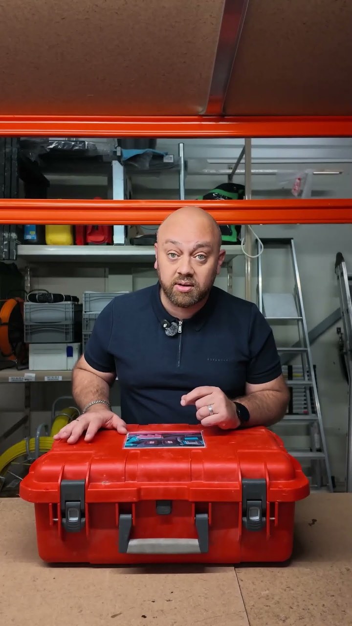 Collega tussen de stellingen in het magazijn van CameraInstallatie met een koffer installatiemateriaal