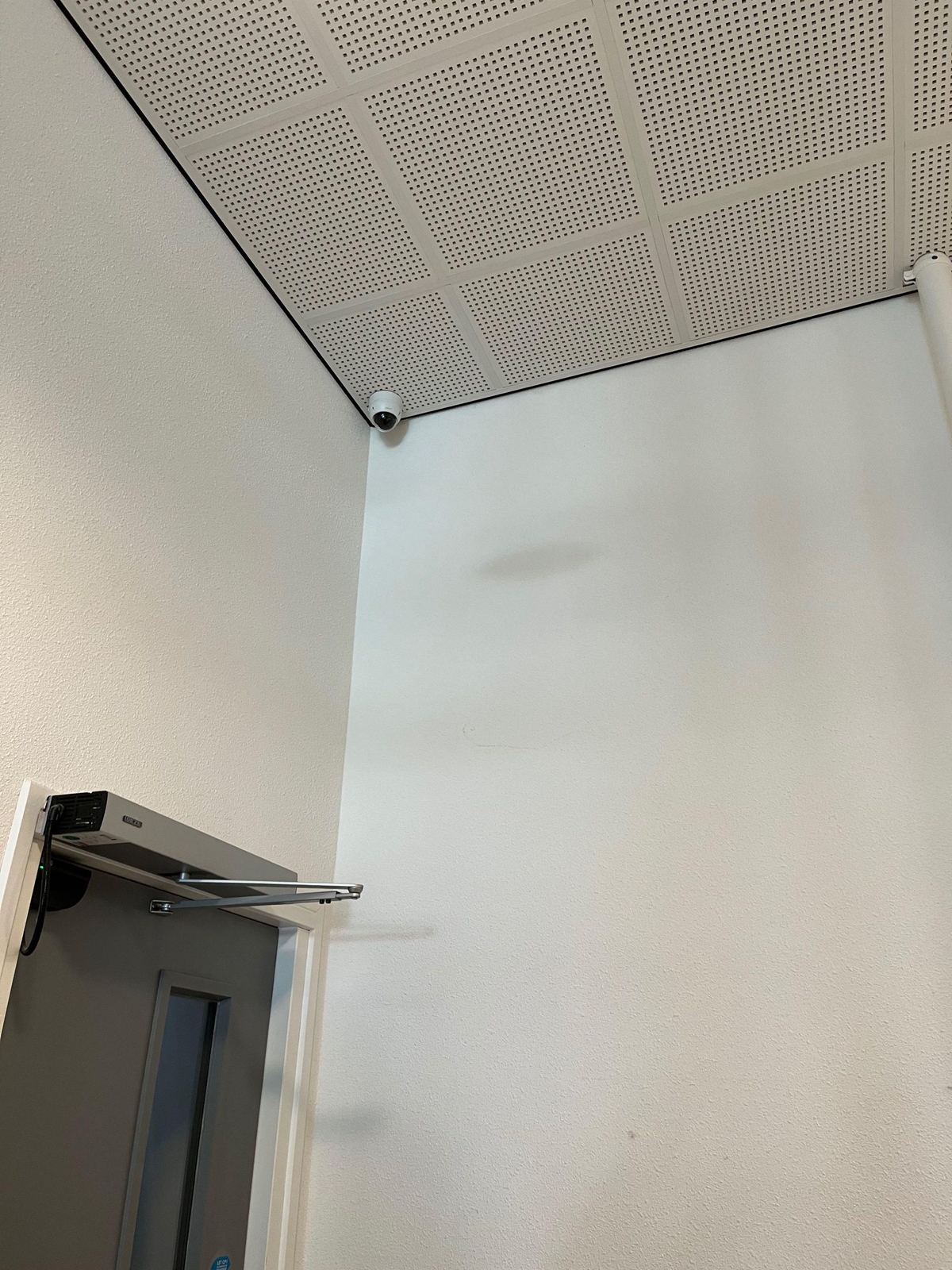 Camera in de hoek van een gang bij een deur met deurdranger in een appartementencomplex