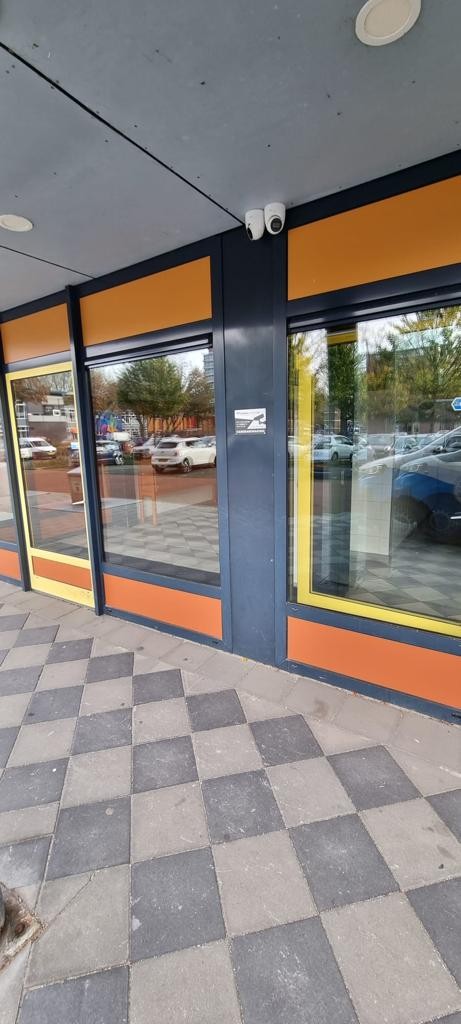 Duocamera onder de luifel op de hoek van het pand, met zicht op het parkeerterrein