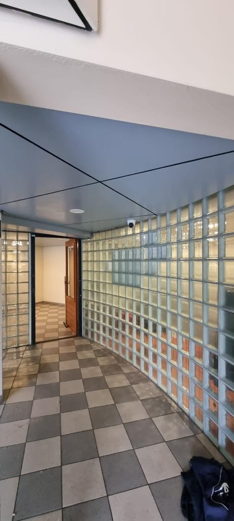 Entreehal met glasbouwstenen, de postkasten van de bewoners en een camera in het plafond