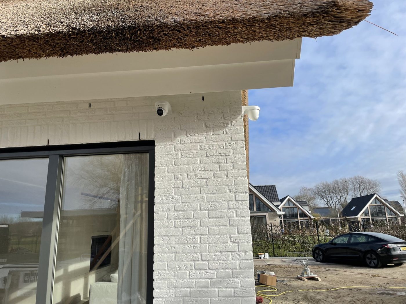 Camera en detectiemelder onder de rieten kap van een vrijstaande villa in het Gooi