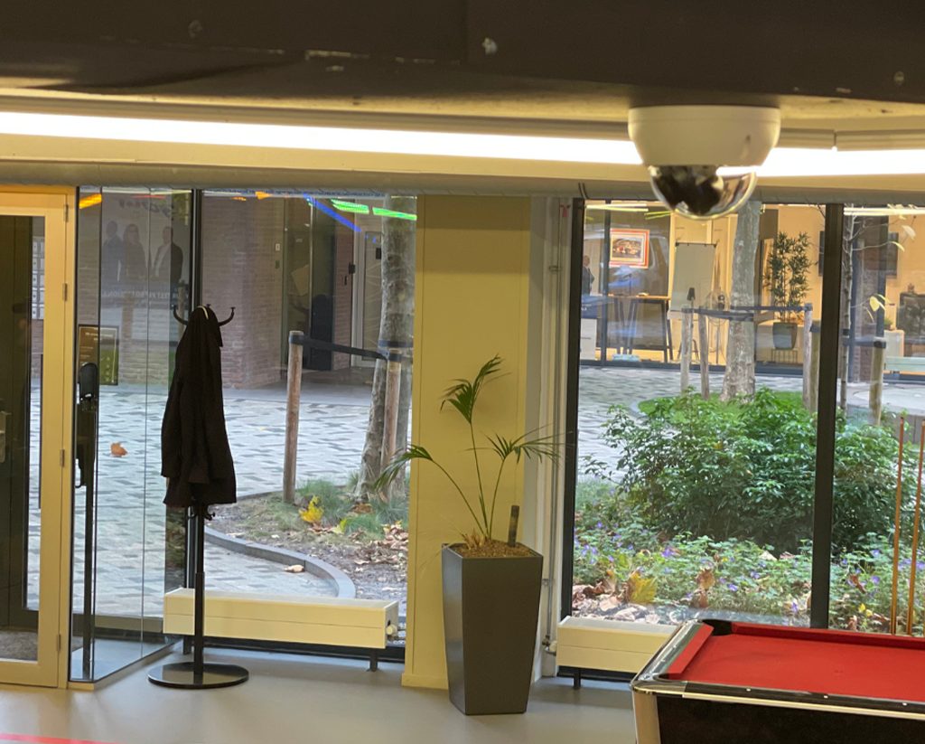 Discrete dome-camera in het plafond van een winkel met zicht op de deur