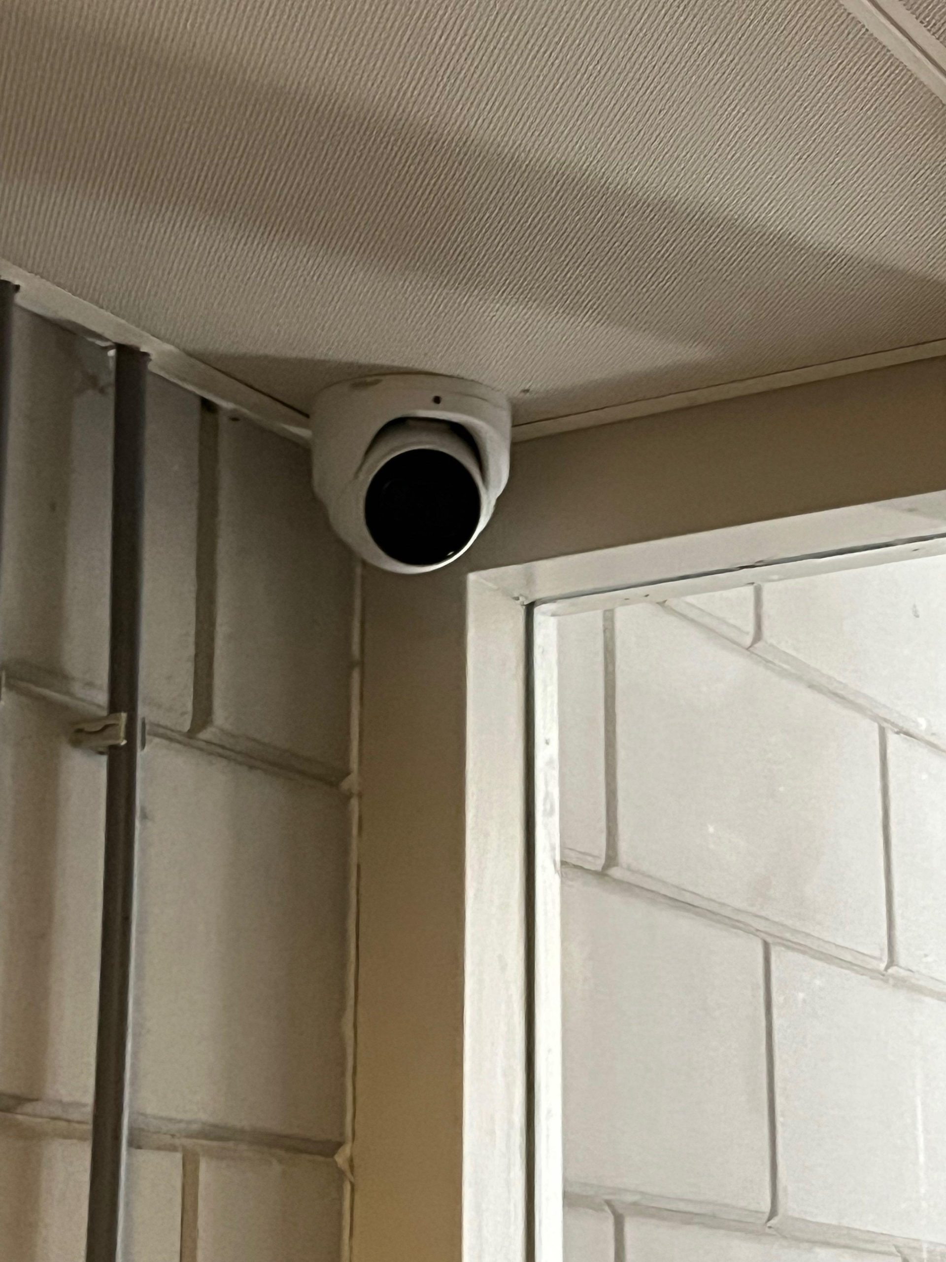 Witte beveiligingscamera gemonteerd tegen het plafond in een binnenruimte