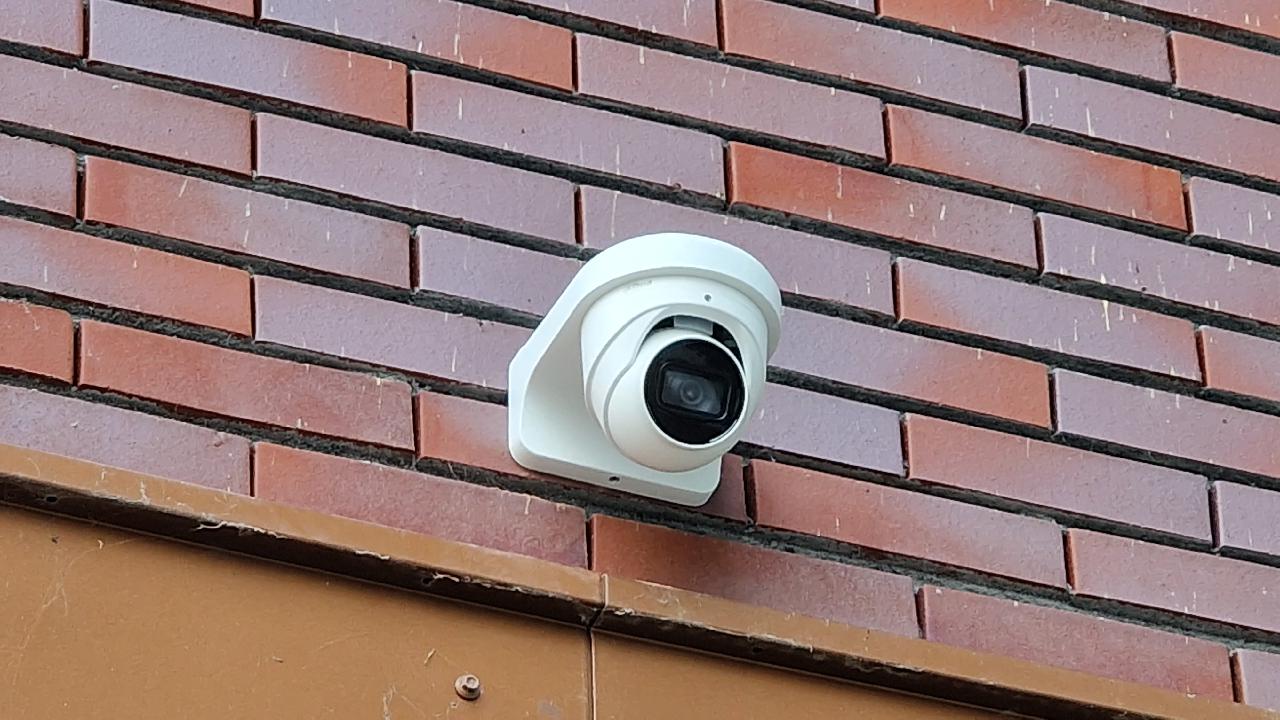 Witte domecamera van CameraInstallatie aan een bakstenen schoolgevel