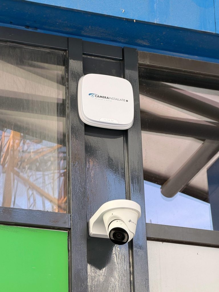 UniFi access point en camera naast elkaar op een stalen ligger in een bedrijfshal