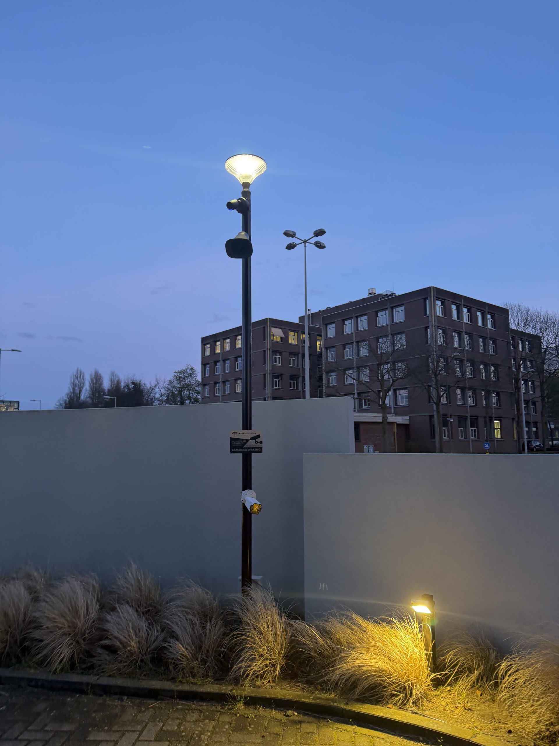 Camera met luidspreker en een camerabewaking-waarschuwingsbord op een mast bij het hotelparkeerterrein