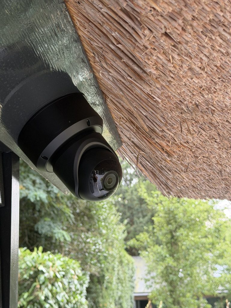 Zwarte beveiligingscamera onder de rietrand van het dak gemonteerd, van dichtbij