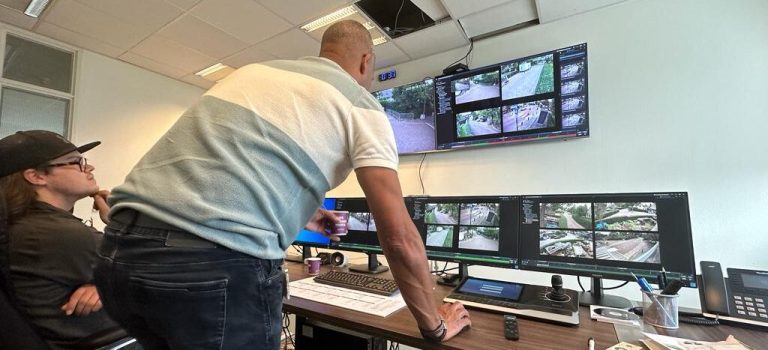 Toezichthouder kijkt mee op meerdere monitoren met live camerabeelden