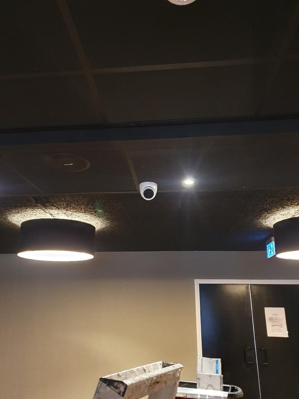 Een camera onopvallend weggewerkt tegen het donkere plafond van een horecaruimte