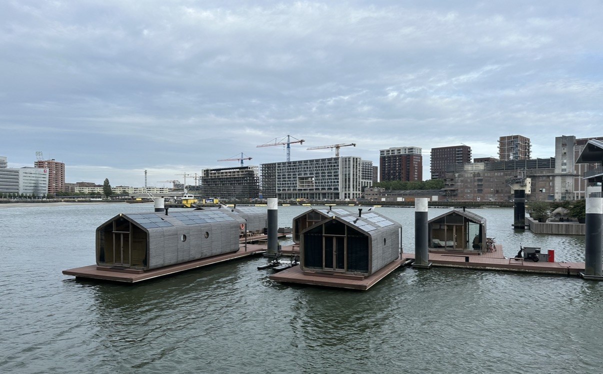 Drie drijvende hotelkamers op het water, met de skyline van de stad op de achtergrond
