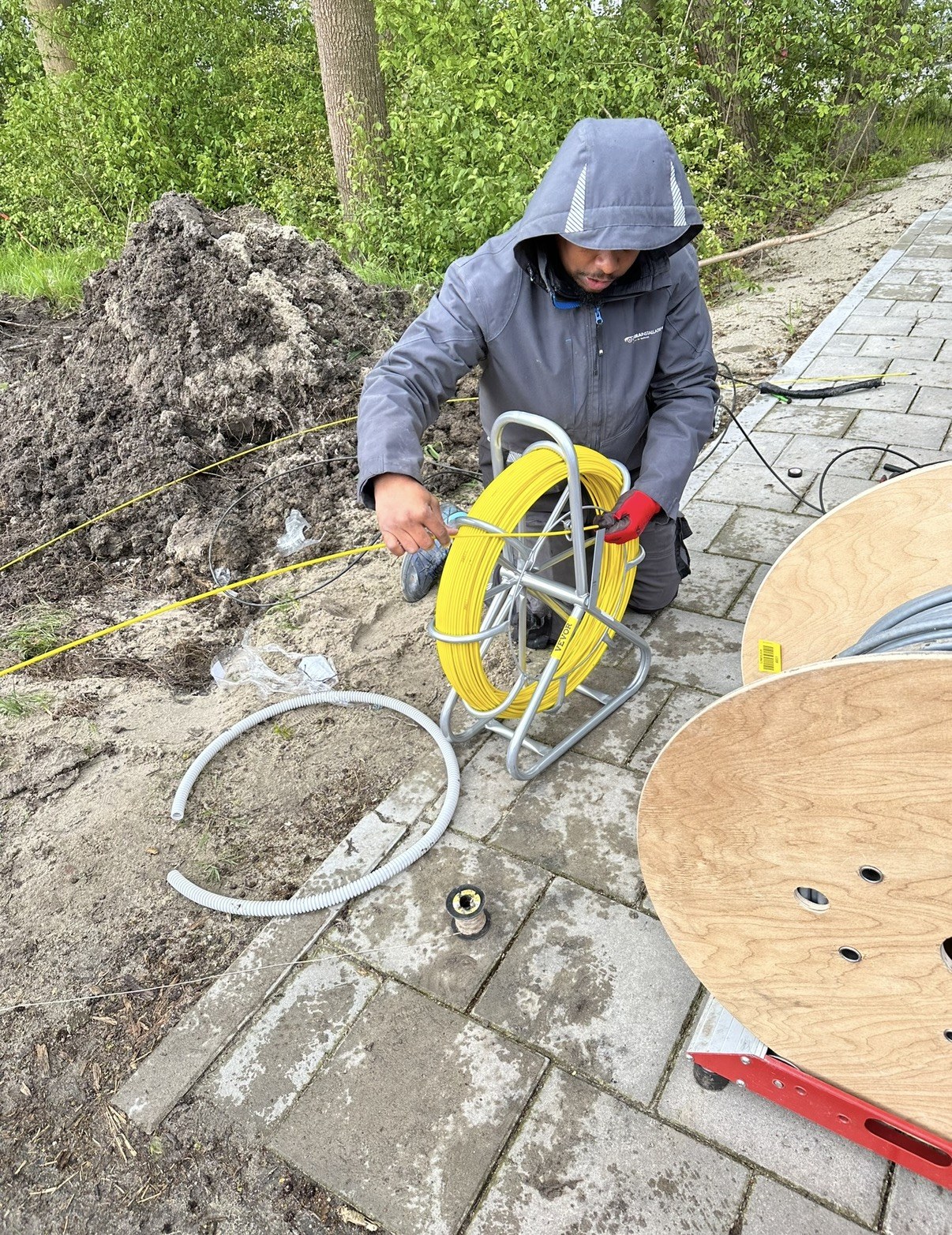 De glasvezel wordt met de rijgveer door de buis getrokken richting de volgende kast
