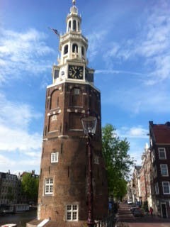 Historisch pand aan de Amsterdamse grachten met de Montelbaanstoren en rondvaartboten op het water