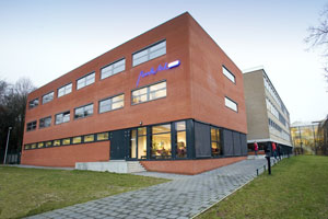 Modern rood bakstenen schoolgebouw met glazen begane grond en gazon ervoor
