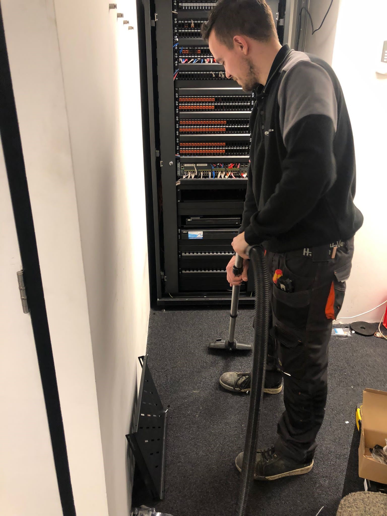 Monteur van CameraInstallatie levert de netwerkkast met patchpanelen en switch netjes op en maakt de technische ruimte schoon