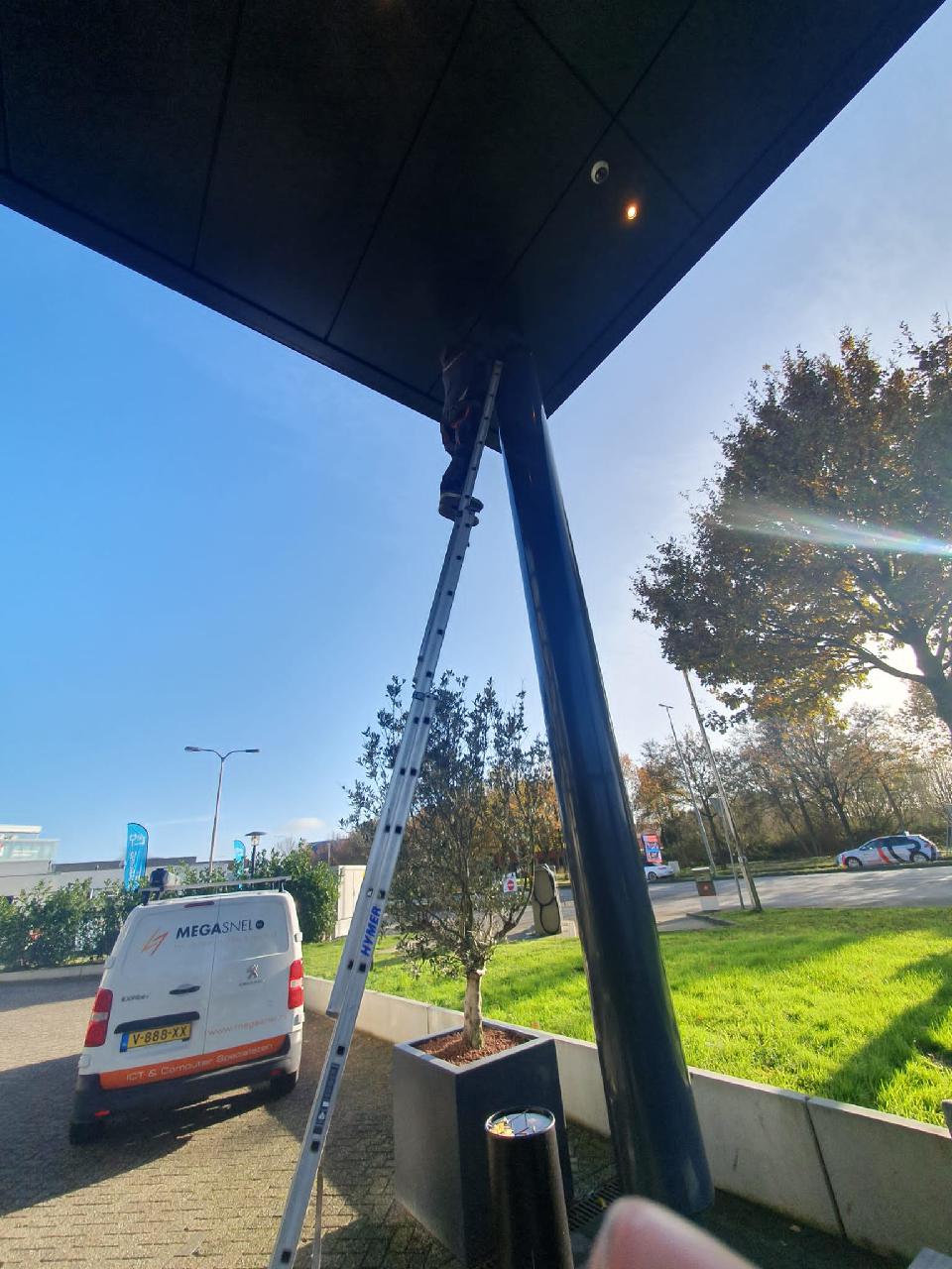 Buiten bij de entree wordt een camera onder de luifel geplaatst