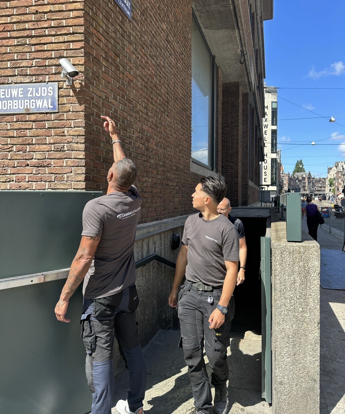 Twee monteurs van CameraInstallatie wijzen de camerapositie aan op de gevel