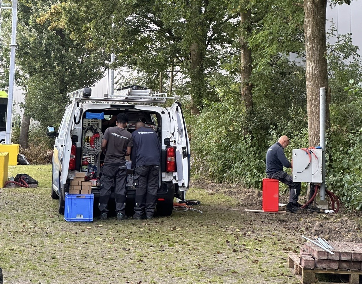 Werken vanuit de bus, terwijl een collega de buitenkast aansluit