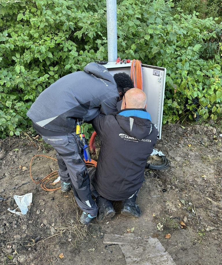 Twee monteurs monteren een buitenkast op een bedrijfsterrein