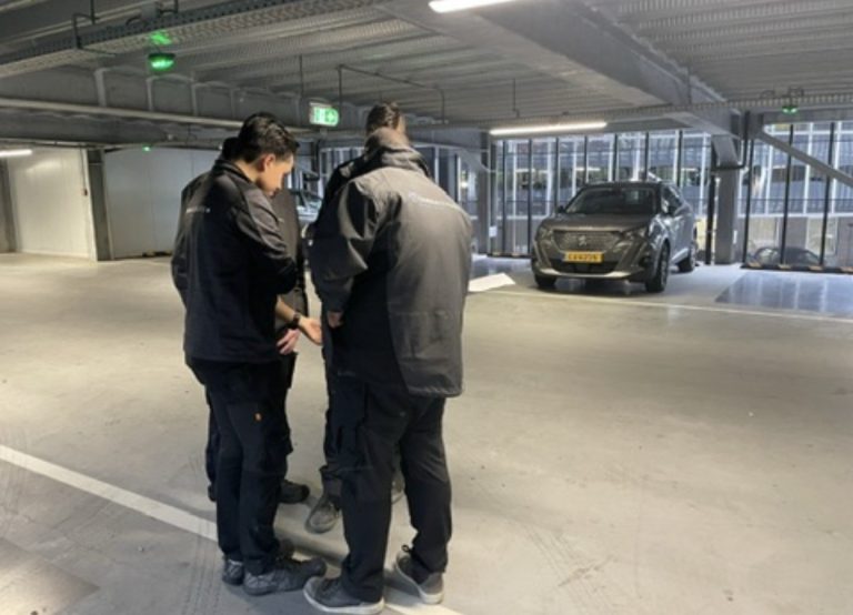 Monteurs van CameraInstallatie overleggen over de camerapositie in een parkeergarage