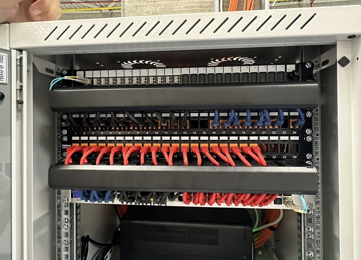In de kast: patchpanelen, gescheiden kleuren per netwerk en een UPS onderin
