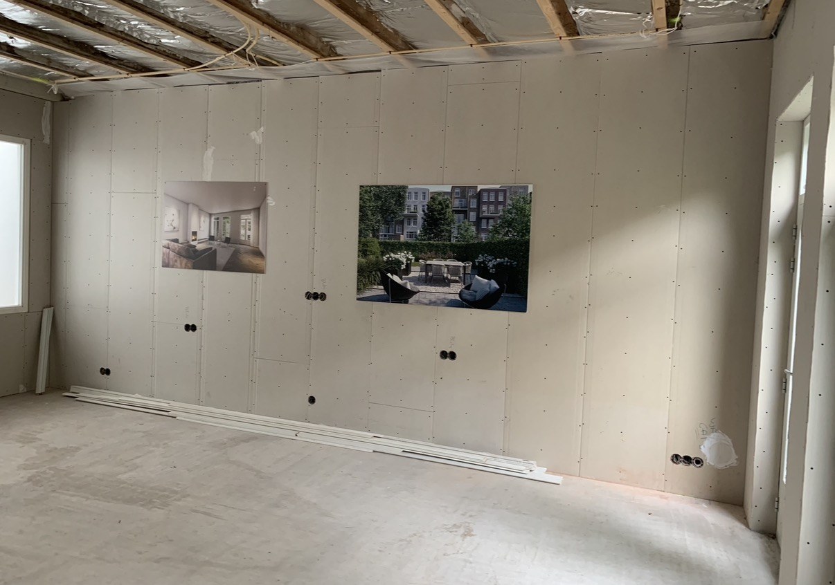 De woning in de ruwbouwfase: de inbouwdozen zitten al in de wand, met de interieurbeelden ernaast geprikt