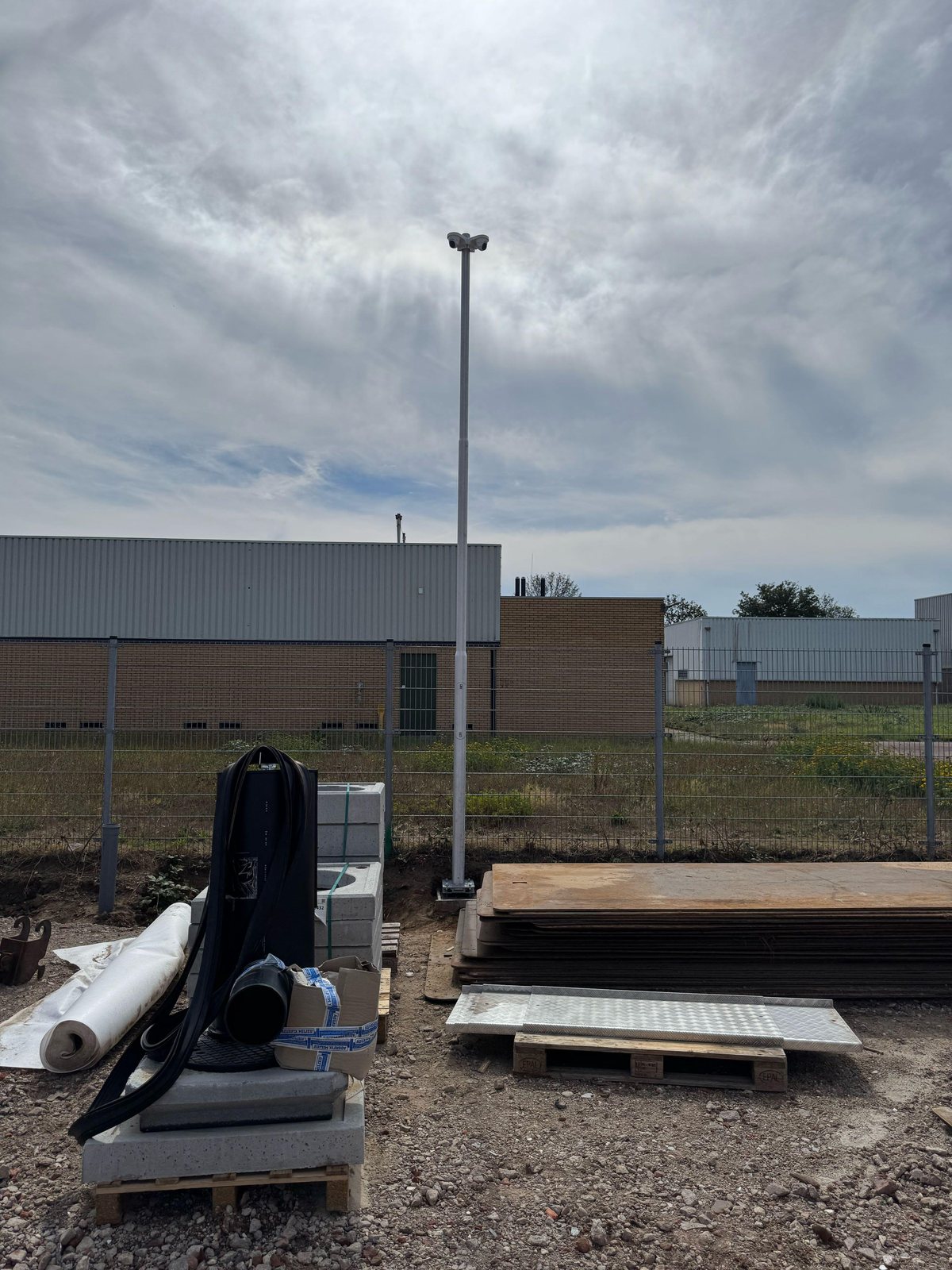 Mobiele cameramast op een bouwterrein, met bouwmateriaal op de voorgrond