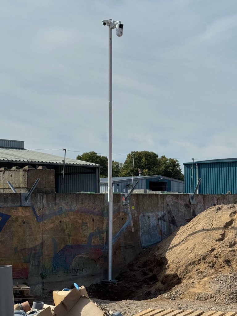Cameramast op een bouwterrein naast een betonnen keerwand