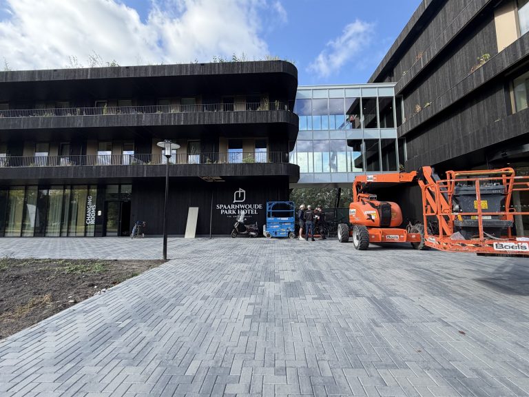 Monteurs in een hoogwerker aan de gevel van een hotel tijdens een cameraproject